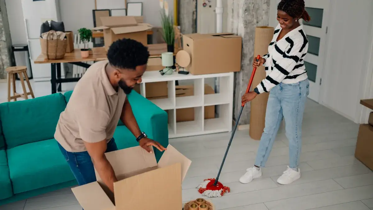 Couple mopping and packing boxes during a home move and clean