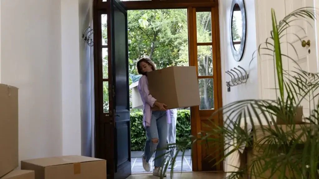 Person carrying a cardboard box through the front door of an Australian period home on moving day