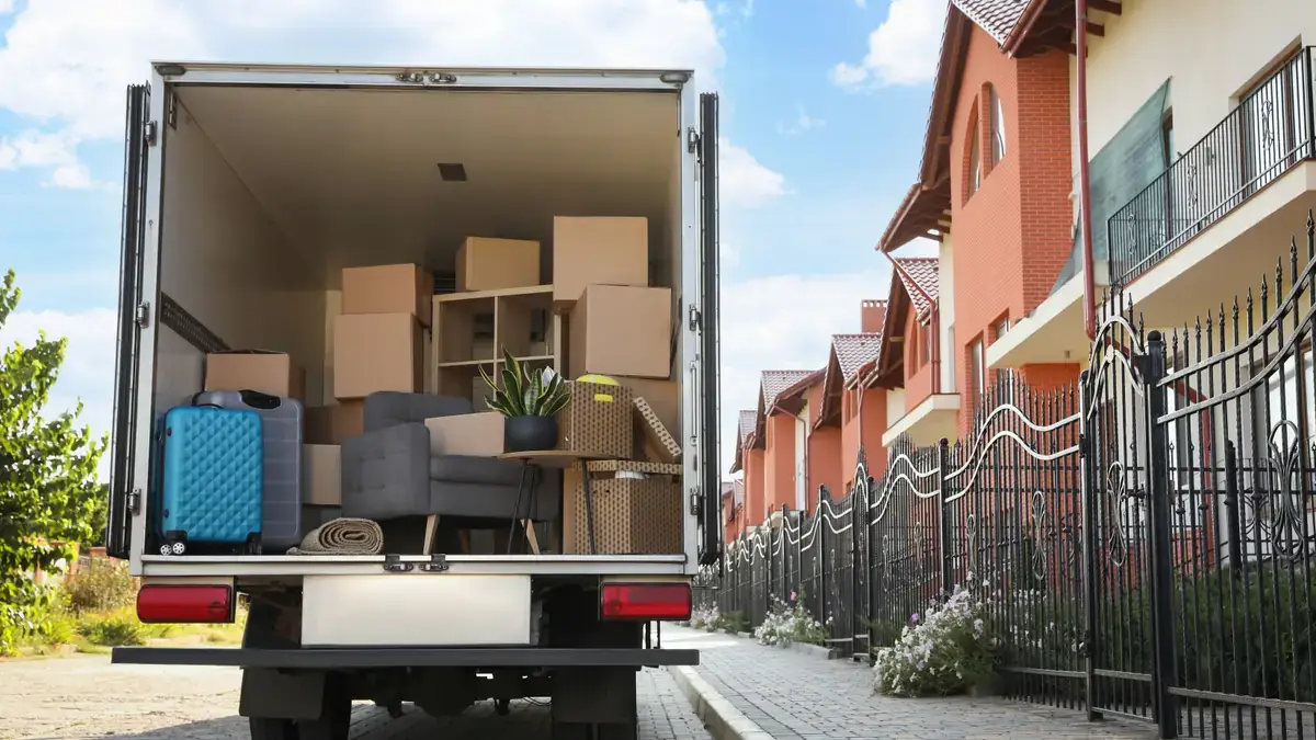 Interior of a moving truck fully loaded with furniture, boxes, a suitcase and household items ready for interstate transport