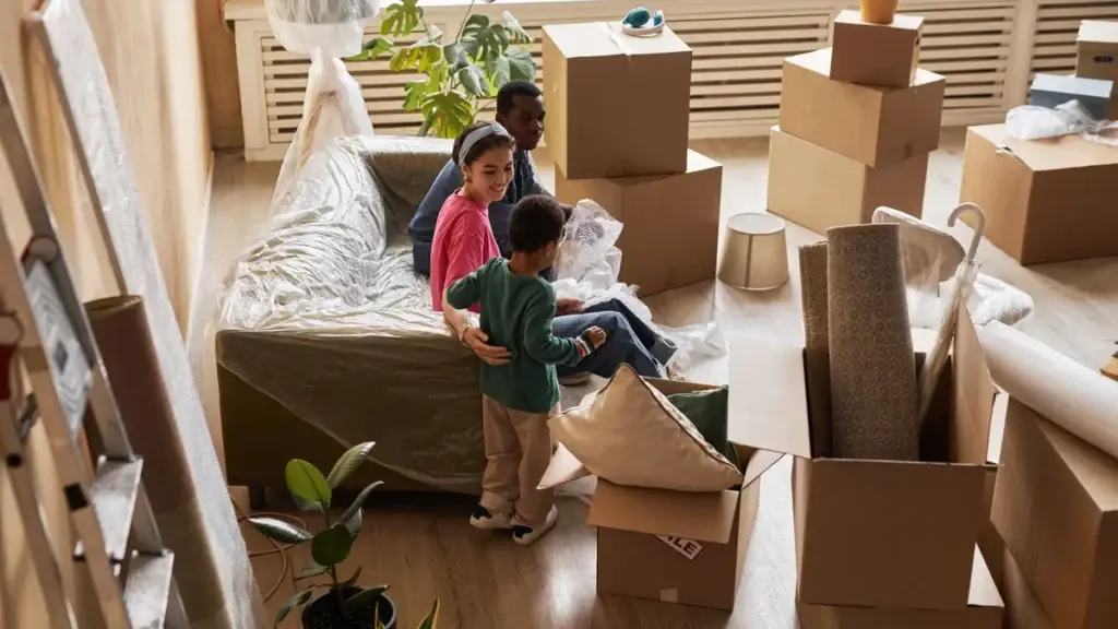 Family with cardboard boxes and plastic-wrapped furniture preparing to move house in Perth