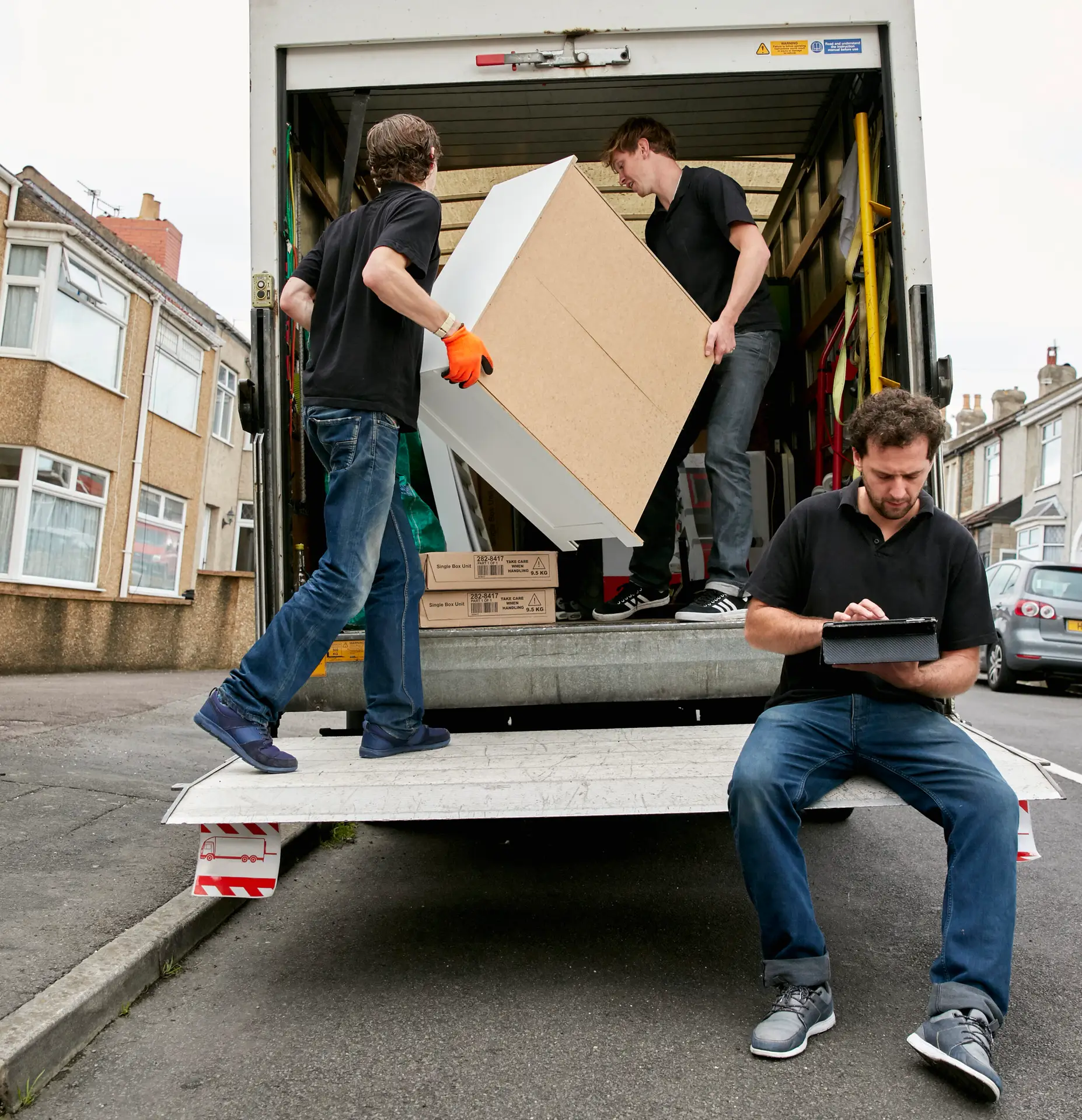 An Urgent Pro rubbish removal provider in Melbourne lifting an old fridge-freezer out of a kitchen and loading it safely onto the truck for recycling, with professional equipment visible in a realistic local service setting