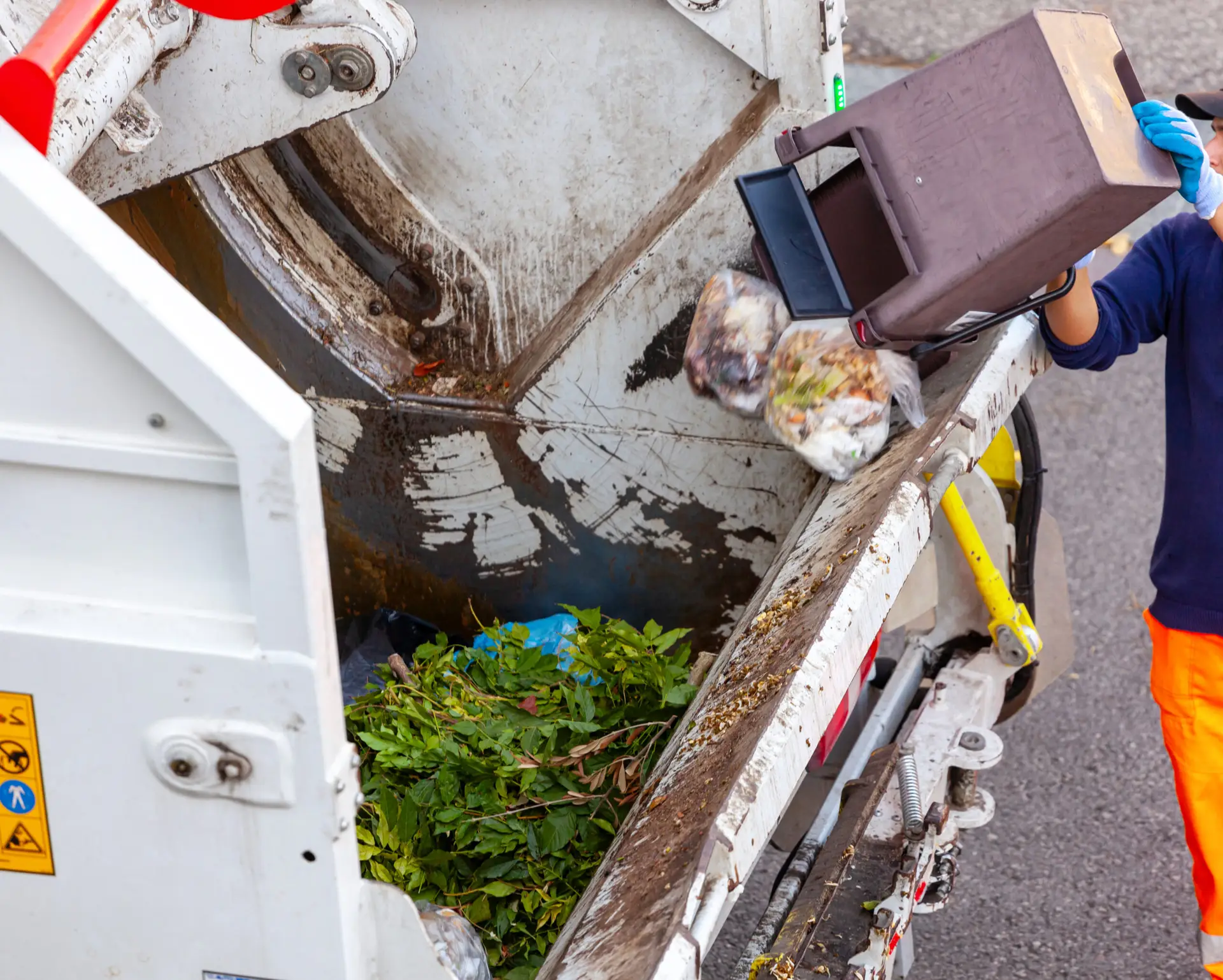 An Urgent Pro rubbish removal provider in Perth collecting pruned branches, grass clippings and garden debris into the truck for green waste disposal, with professional equipment visible in a realistic local service setting