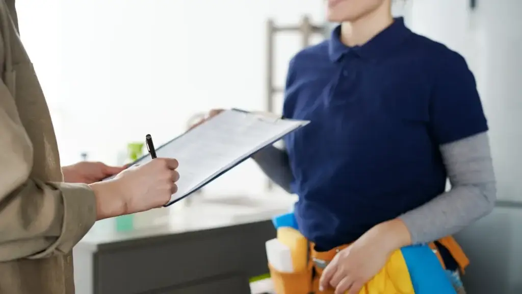 Customer signing a service agreement document with a professional provider in a home kitchen