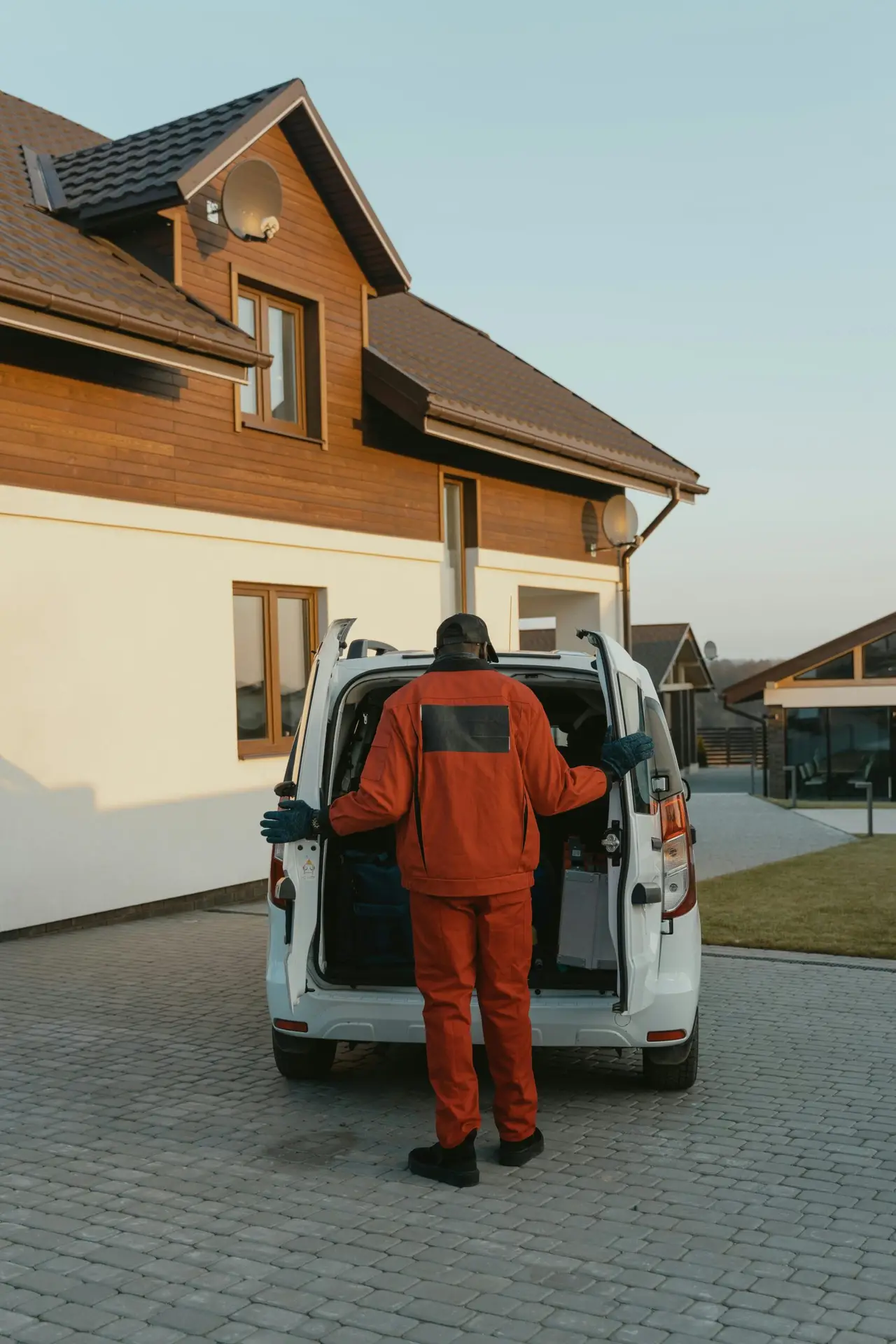 An Urgent Pro cleaner standing at the entry of a Brisbane rental property holding the property access keys and a cleaning caddy, about to begin the vacate clean for a tenant who is in the process of moving out