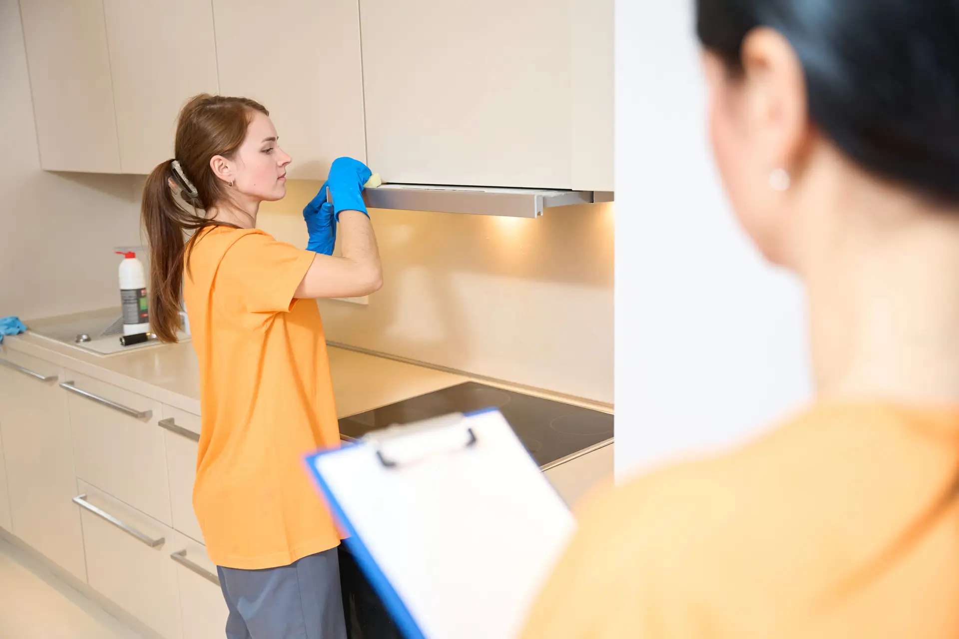 An Urgent Pro team member at the entry of a fully cleaned Gold Coast rental apartment holding a completed inspection checklist with all rooms ticked off, standing in front of clean floors and a spotless hallway ready for the agent's final inspection