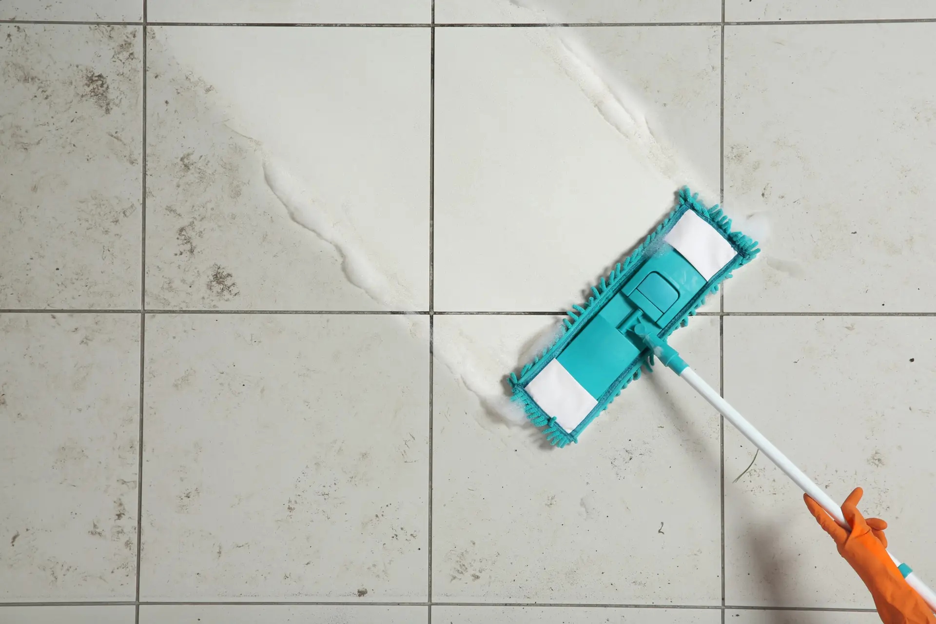 An Urgent Pro cleaner scrubbing the inside of a Perth rental shower recess — cleaning the shower screen, grouting the floor and polishing the rose and tapware with a full set of bathroom cleaning products visible on the shower shelf