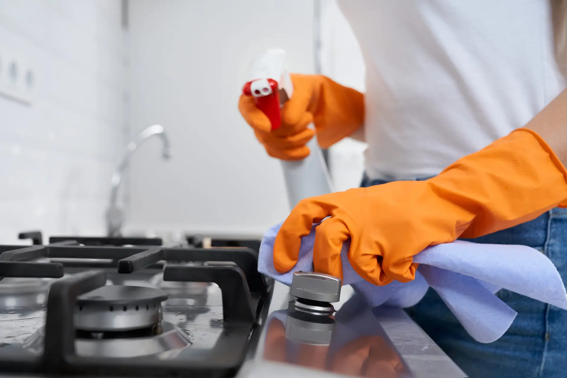 An Urgent Pro cleaner wearing yellow rubber gloves applying heavy-duty degreaser to the interior of a rental oven in Sydney, with the oven door removed and the element and side walls being scrubbed with a scourer pad