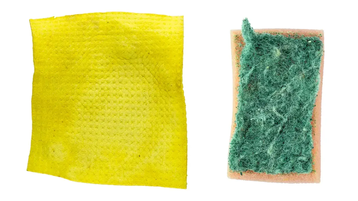 Yellow soft non-woven cleaning cloth on the left and worn green abrasive scouring sponge on the right on a white background